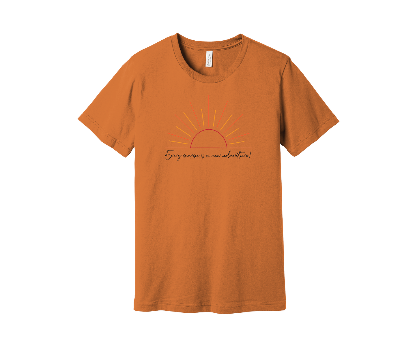 A muted orange T-shirt features a graphic of a stylized orange and yellow sunrise above a handwritten cursive message in black that reads, "Every sunrise is a new adventure!" The shirt has a simple and modern design.