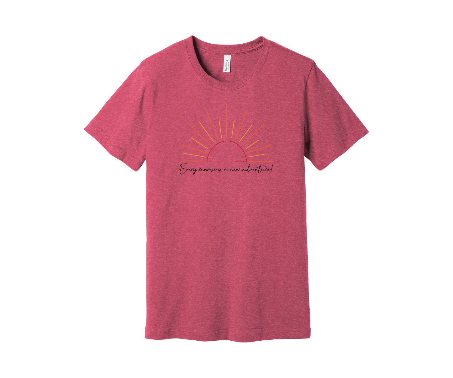 A pink heather T-shirt features a graphic of a stylized orange and yellow sunrise above a handwritten cursive message in black that reads, "Every sunrise is a new adventure!" The shirt has a simple and modern design.