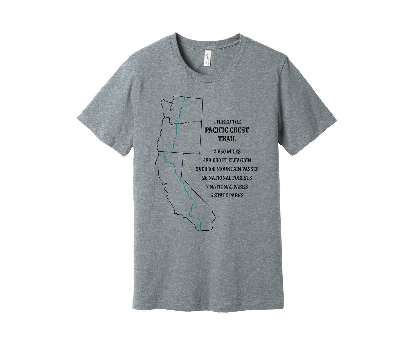 A light gray heather T-shirt displays a black map outline of the states of California, Oregon and Washington and the route of the Pacific Crest Trail in teal. Text on the shirt reads: "I Hiked the Pacific Crest Trail," and lists details: 2,650 miles, 489,500 ft elevation gain, Over 60 Mountain Passes, 28 National Forests, 7 National Parks, 5 State Parks.