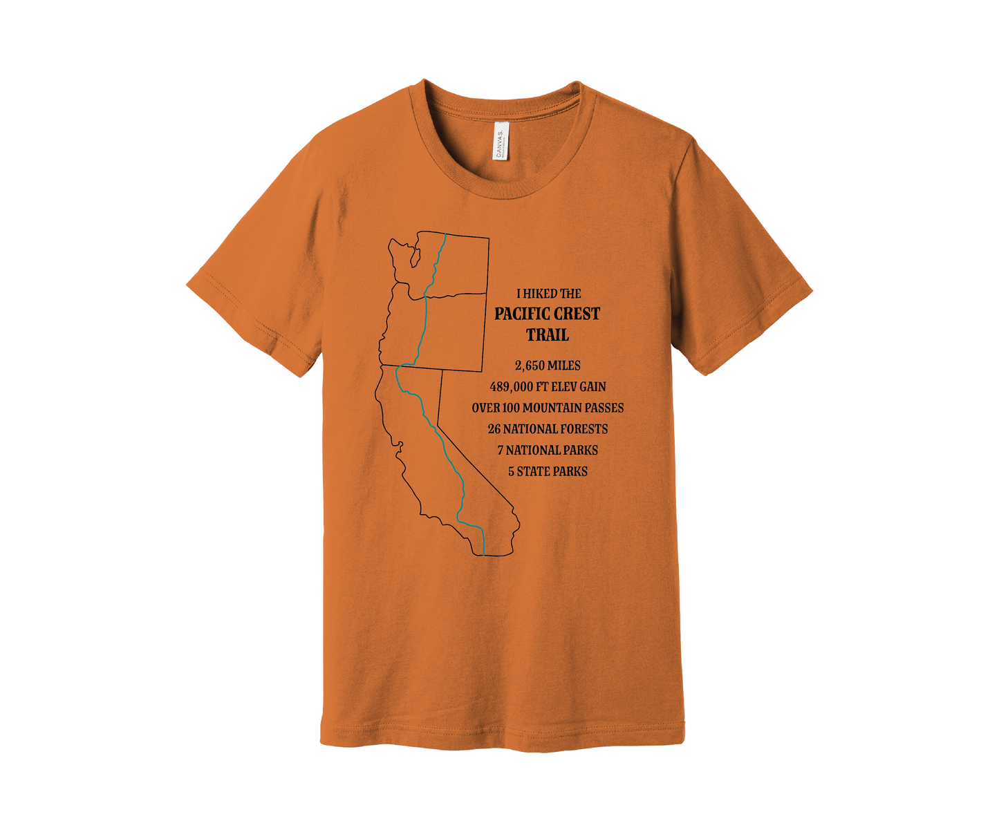 A muted orange T-shirt displays a black map outline of the states of California, Oregon and Washington and the route of the Pacific Crest Trail in teal. Text on the shirt reads: "I Hiked the Pacific Crest Trail," and lists details: 2,650 miles, 489,500 ft elevation gain, Over 60 Mountain Passes, 28 National Forests, 7 National Parks, 5 State Parks.